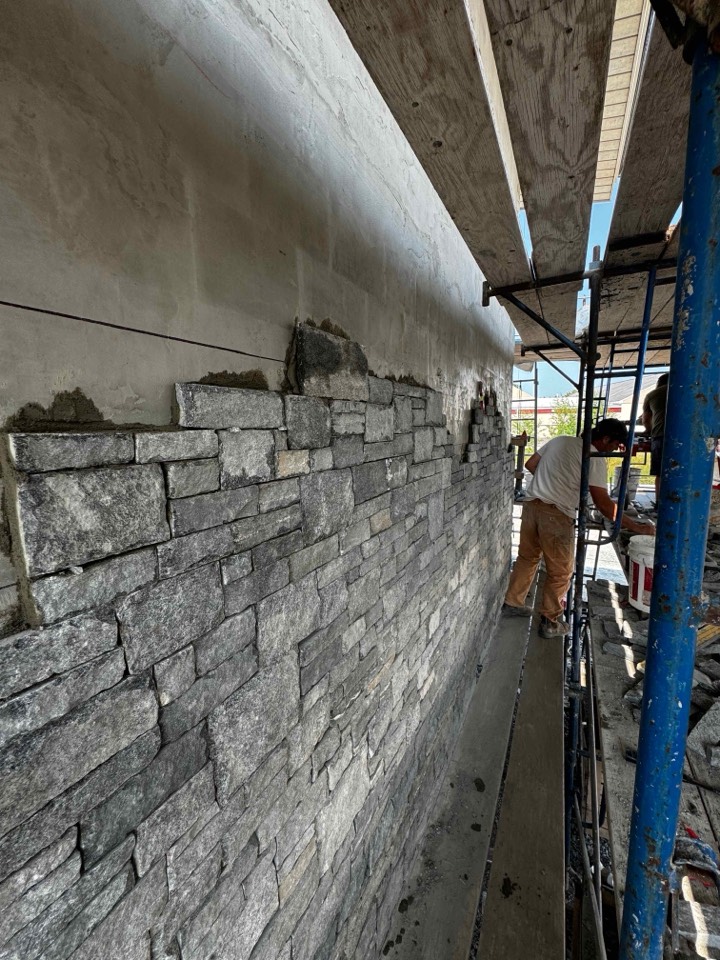 Foxpoint crew building a ledgestone wall along scaffolding