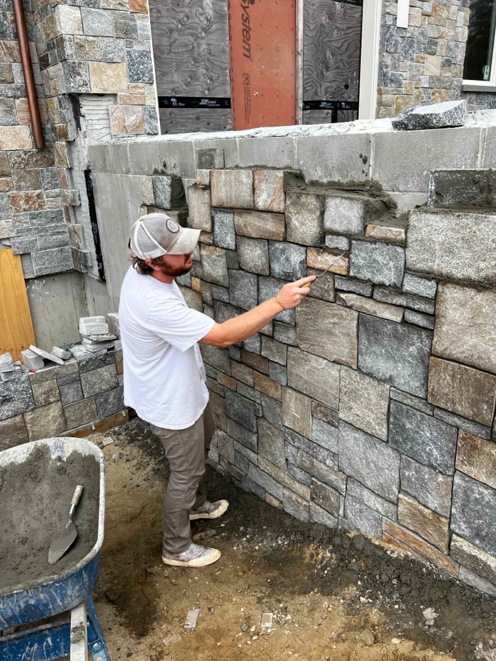 Mason tooling mortar joints on a granite veneer wall